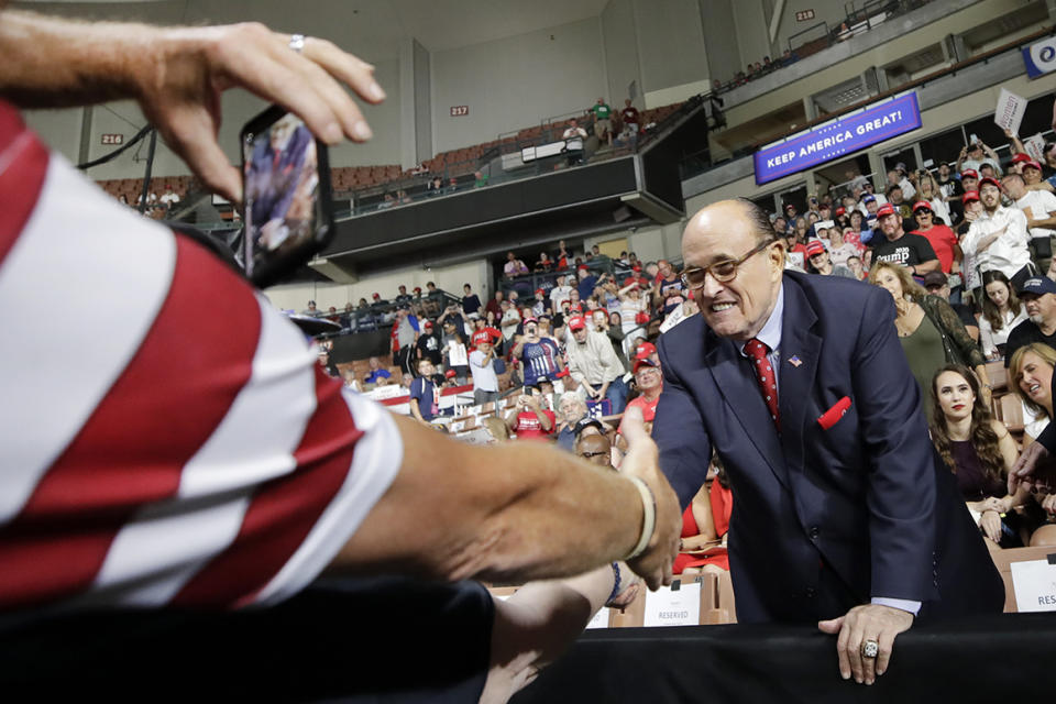 Former New York City Mayor Rudy Giuliani shakes a hand as he arrives to President Donald Trump's campaign rally, Thursday, Aug. 15, 2019, in Manchester, N.H. (AP Photo/Elise Amendola)