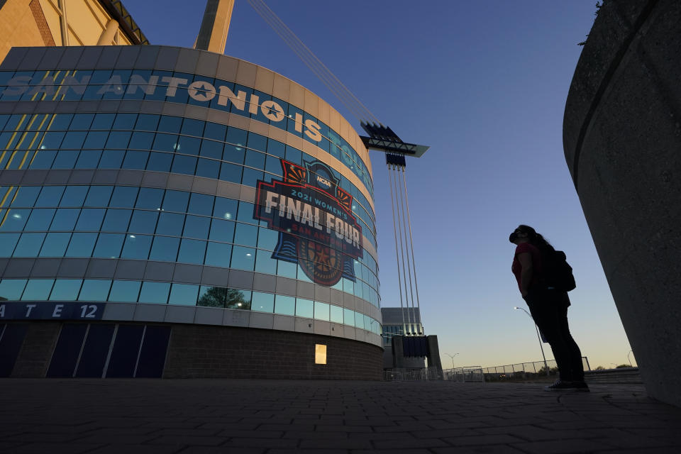 FILE - A visitor looks up at the logo for the Women's Final Four in San Antonio, as the city prepares to host the Women's NCAA College Basketball Championship, in this March 18, 2021, file photo. A law firm hired to investigate gender equity concerns at NCAA championship events released a blistering report Tuesday, Aug. 3, 2021, that recommended holding the men's and women's Final Fours at the same site and offering financial incentives to schools to improve their women's basketball programs. (AP Photo/Eric Gay, File)