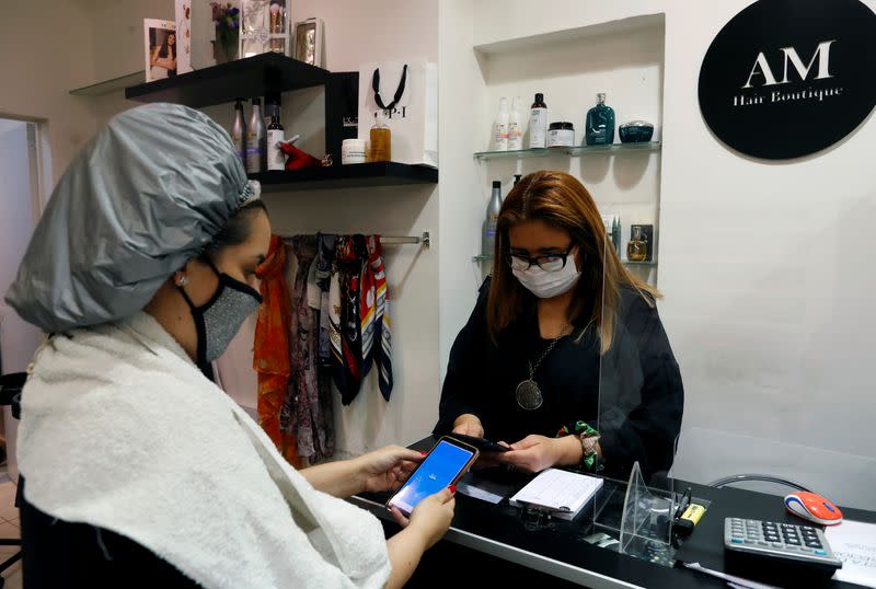 Muriel, a client of AM hair salon, pays to the owner Andrea Manoli using Mercado Pago app, in Buenos Aires