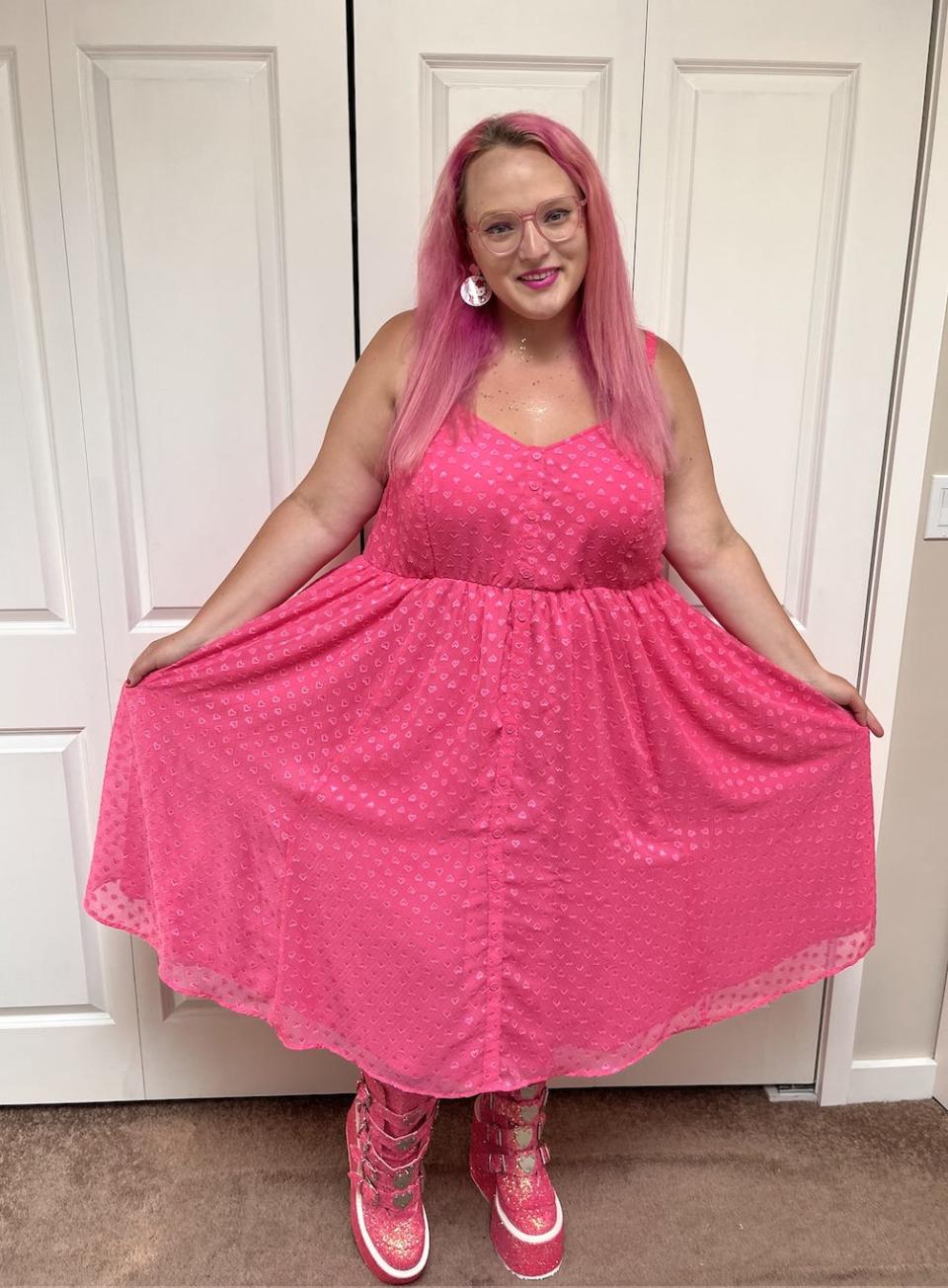 The writer wearing a hot pink dress with glittery pink platform shoes