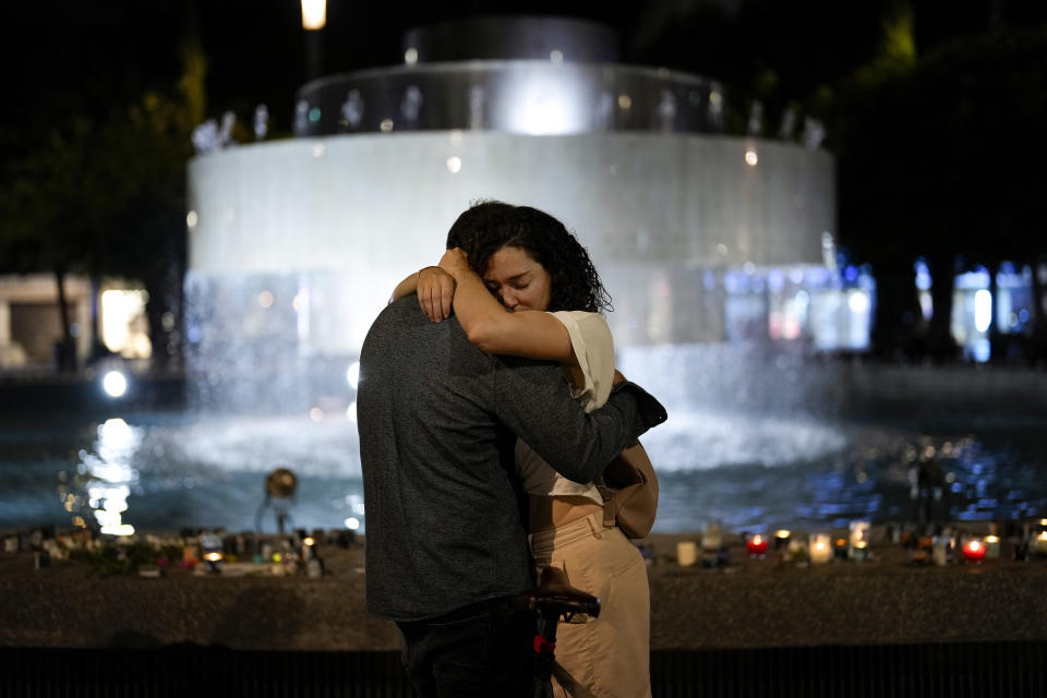 A couple hugs next to candles lighted in honour of victims of the Hamas attacks during a vigil at the Dizengoff square in central Tel Aviv, Israel, Friday, Oct. 13, 2023. (AP Photo/Francisco Seco)