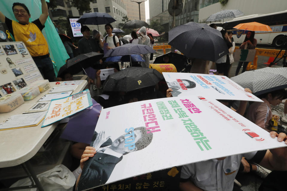 Protesters hold their banners in the rain during a rally demanding full compensation and an apology for wartime sex slaves from Japanese government in front of the Japanese Embassy in Seoul, Wednesday, July 17, 2019. In his strongest comments yet on a growing trade dispute, South Korean President Moon Jae-in urged Japan on Monday to lift recently tightened controls on high-tech exports to South Korea, which he said threaten to shatter the countries' economic cooperation and could damage Japan more than South Korea. The signs read: "Denounce, Abe's government." (AP Photo/Ahn Young-joon)