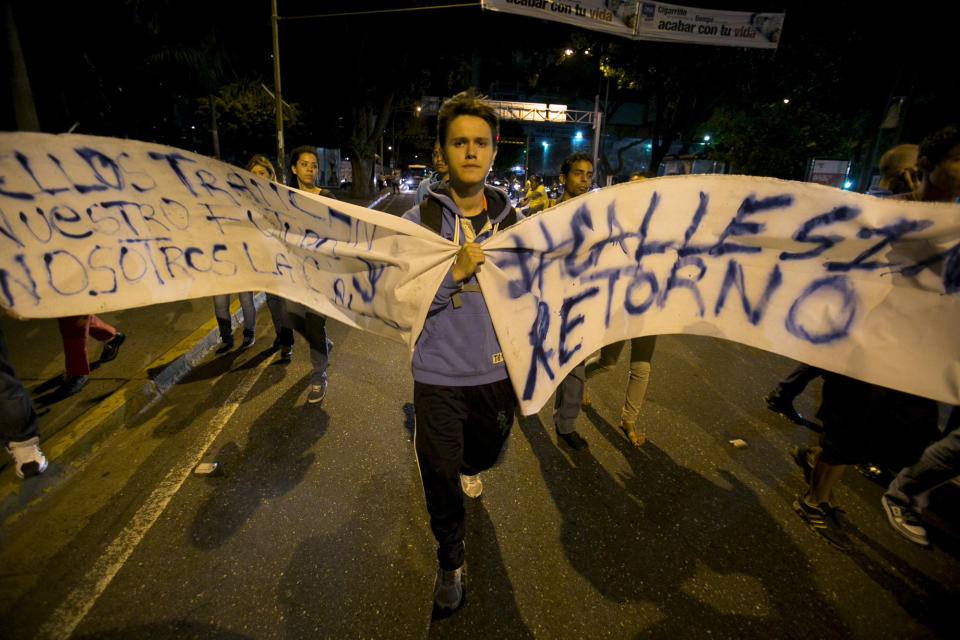 A demonstrator carries banners during a protest against the detention of four students in Caracas, Venezuela, Saturday, Feb. 8, 2014. The detained students were arrested in Tachira state on Friday while protesting crime. The protests are part of a civil movement called "Street with no return" that is calling for street protests against the government of Venezuela's President Nicolas Maduro. (AP Photo/Alejandro Cegarra)