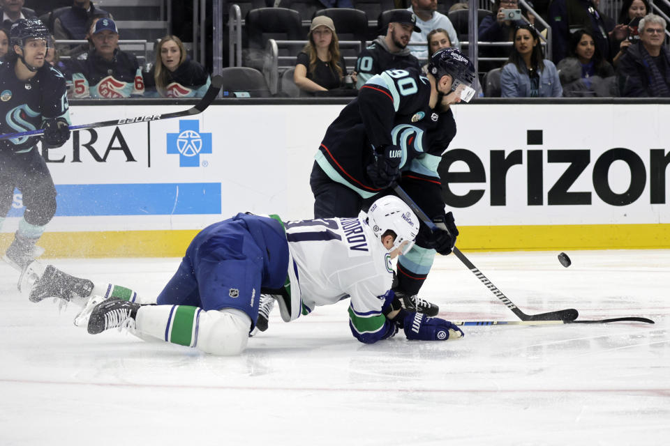 Seattle Kraken left wing Tomas Tatar (90) and Vancouver Canucks defenseman Nikita Zadorov compete for the puck during the third period of an NHL hockey game Thursday, Feb. 22, 2024, in Seattle. (AP Photo/John Froschauer)