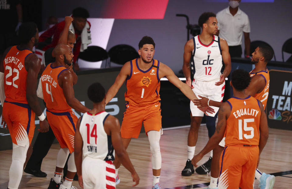 Phoenix Suns guard Devin Booker (1) celebrates with teammates in the first half of an NBA basketball game against the Washington Wizards in Lake Buena Vista, Fla., Friday, July 31, 2020. (Kim Klement/Pool Photo via AP)