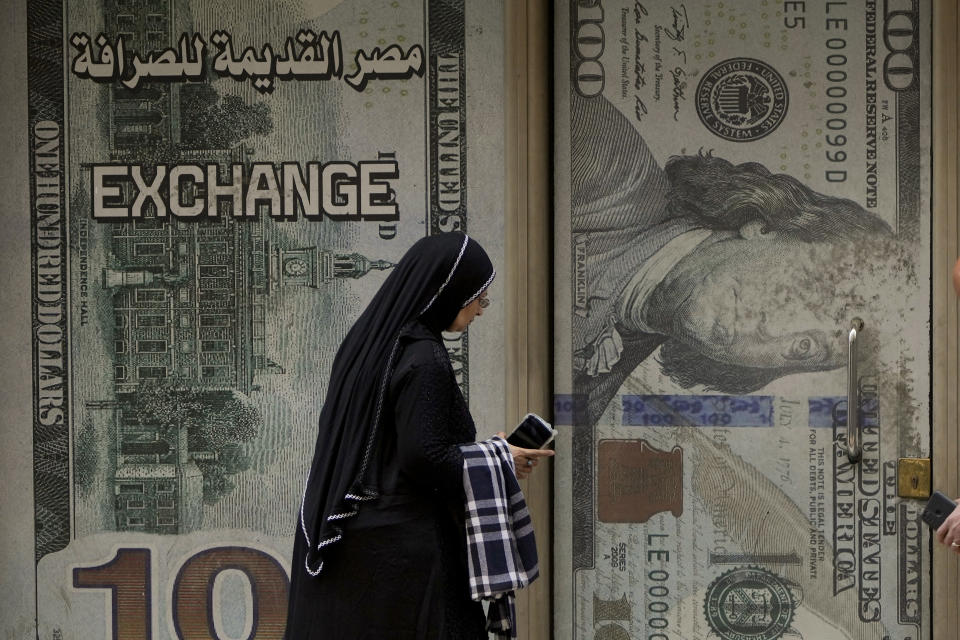 An Egyptian woman walks past an exchange office in Cairo, Egypt, Wednesday, March 6, 2024. The Egyptian pound slipped sharply against the dollar on Wednesday after the Central Bank of Egypt raised its main interest rate and said it would allow the currency's exchange rate to be set by market forces. (AP Photo/Amr Nabil)