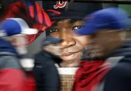 FILE - In this Oct. 1, 2016, file photo, fans at walk past a photograph of Boston Red Sox's David Ortiz before a baseball game against the Toronto Blue Jays at Fenway Park in Boston. Ortiz was back in Boston for medical care after authorities said the former Red Sox slugger affectionately known as Big Papi was ambushed by a gunman at a bar in his native Dominican Republic. A plane carrying the 43-year-old retired athlete landed Monday night, June 10, 2019, after a flight from the Dominican Republic, the team said. (AP Photo/Michael Dwyer, File)