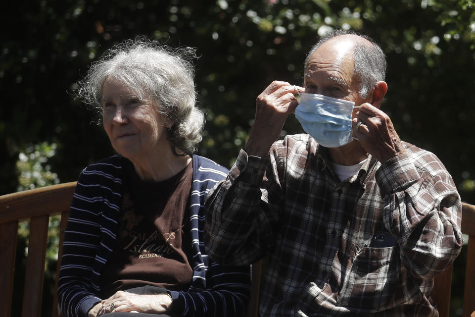 Larry Yarbroff, right, adjusts his mask as he sits with his wife, Mary, while visiting her at Chaparral House in Berkeley, Calif., Friday, July 10, 2020. For months, families have pined to see their loved ones in California's skilled nursing facilities, which have been shut down to outside visitors amid the coronavirus pandemic. California's health authorities recently issued guidance for visits to resume at these facilities, but so far, few appear to be happening as infection rates surge in many communities. (AP Photo/Jeff Chiu)