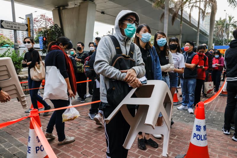 A supporter of pro-democracy activists holds a chair while queuing up to attend a court hearing over the national security law outside West Kowloon Magistrates' Courts, in Hong Kong