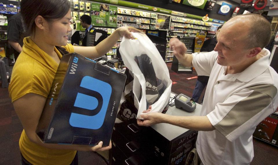 GameStop employee Lani Girran hands over a Wii U system to Kevin Owande, 51, of Renton, Wash., on a busy Black Friday at the GameStop Southcenter store in Seattle on Friday, Nov. 23, 2012. Owande was up early on Black Friday to purchase Wii U, one of the hottest products this holiday season. (Photo by Stephen Brashear/Invision for Nintendo/AP Images)