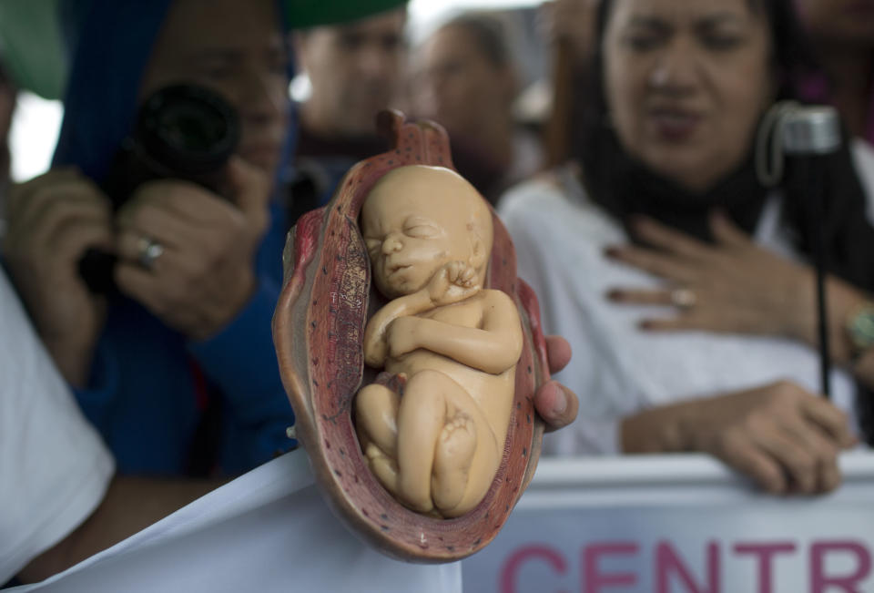 A demonstrator holds a plastic doll shaped like a fetus during a Catholic church event against the legalization of abortion, in Rio de Janeiro, Brazil, Thursday, Aug. 2, 2018. A public hearing to discuss the decriminalization of abortion in Latin America's biggest country will be held Friday at Brazil's Supreme Court. (AP Photo/Silvia Izquierdo)