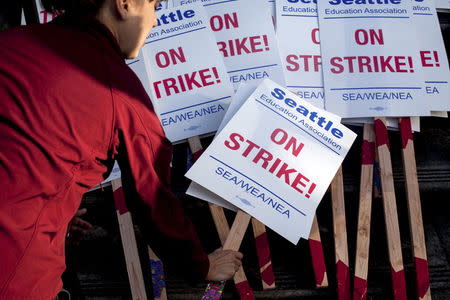 A teacher grabs a sign before walking the picket line as teachers strike outside Roosevelt High School in Seattle, Washington September 9, 2015. REUTERS/Matt Mills McKnight