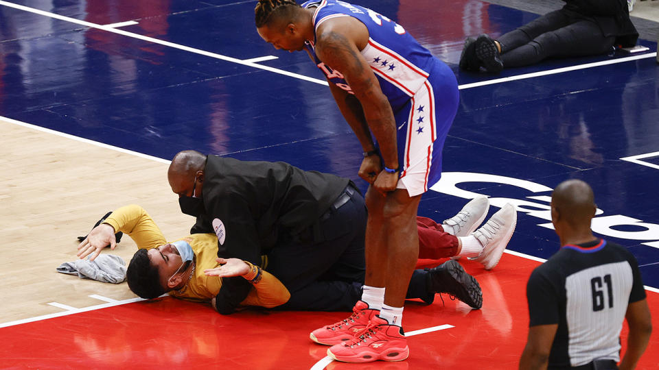 Security lies on top of a fan who ran onto the court during the Wizards' playoff win over Philadelphia.