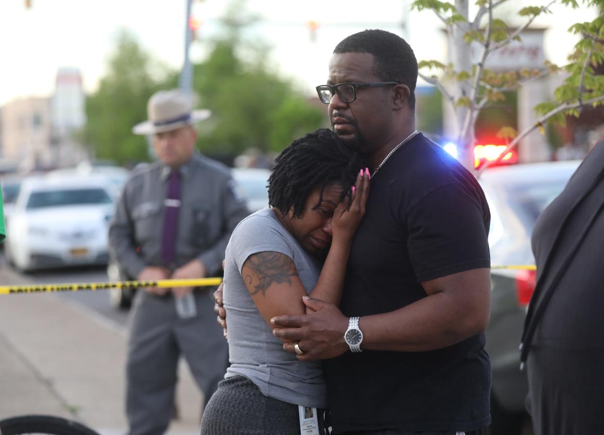 Takesha Leonard is held by her husband, Shawn,  after 10 people were killed in a shooting at a grocery store in Buffalo, N.Y., on May 14. An 18-year-old allegedly shot people inside and outside the Tops Friendly Markets.