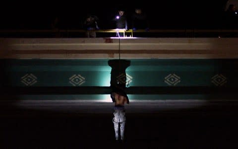 Forensic experts work at a crime scene where the body of a man was found hanging from a bridge at the entrance to Ciudad Juarez - Credit: HERIKA MARTINEZ/ AFP