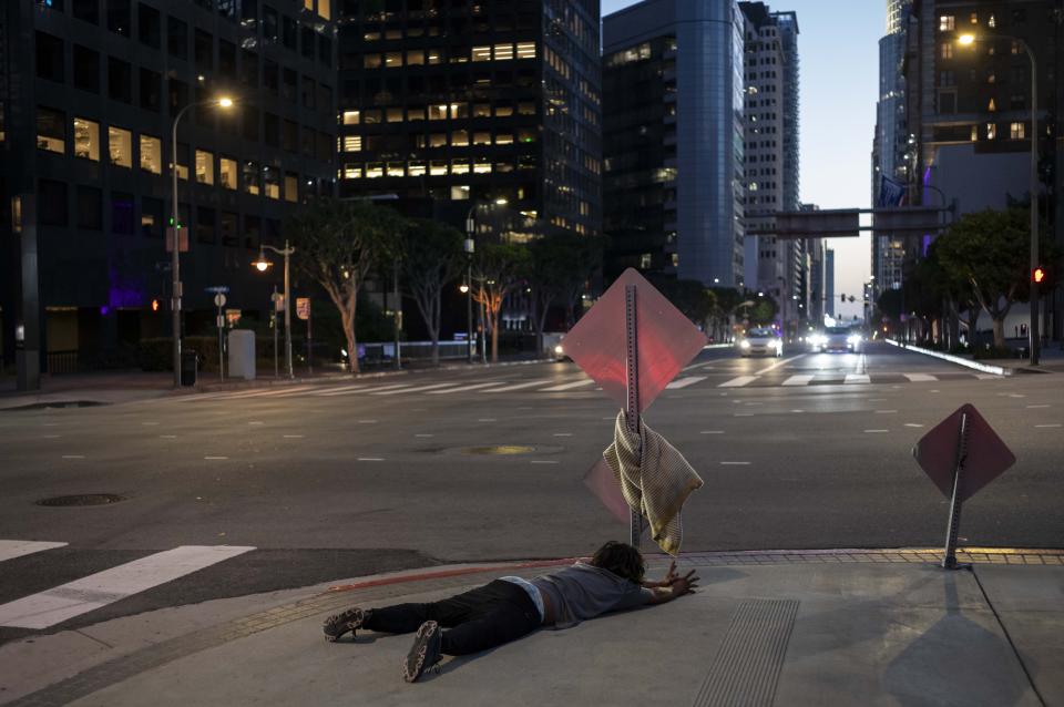 A homeless man screams and extends his arms while lying on a sidewalk as if to reach for something unseen in downtown Los Angeles, Friday, Oct. 13, 2023.(AP Photo/Jae C. Hong)