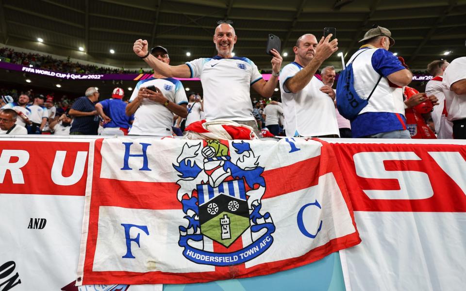 A fan of England poses with a Huddersfield Town flag during the FIFA World Cup Qatar 2022 Group B match between Wales and England at Ahmad Bin Ali Stadium on November 29, 2022 in Doha, Qatar. - Robbie Jay Barratt - AMA/Getty Images
