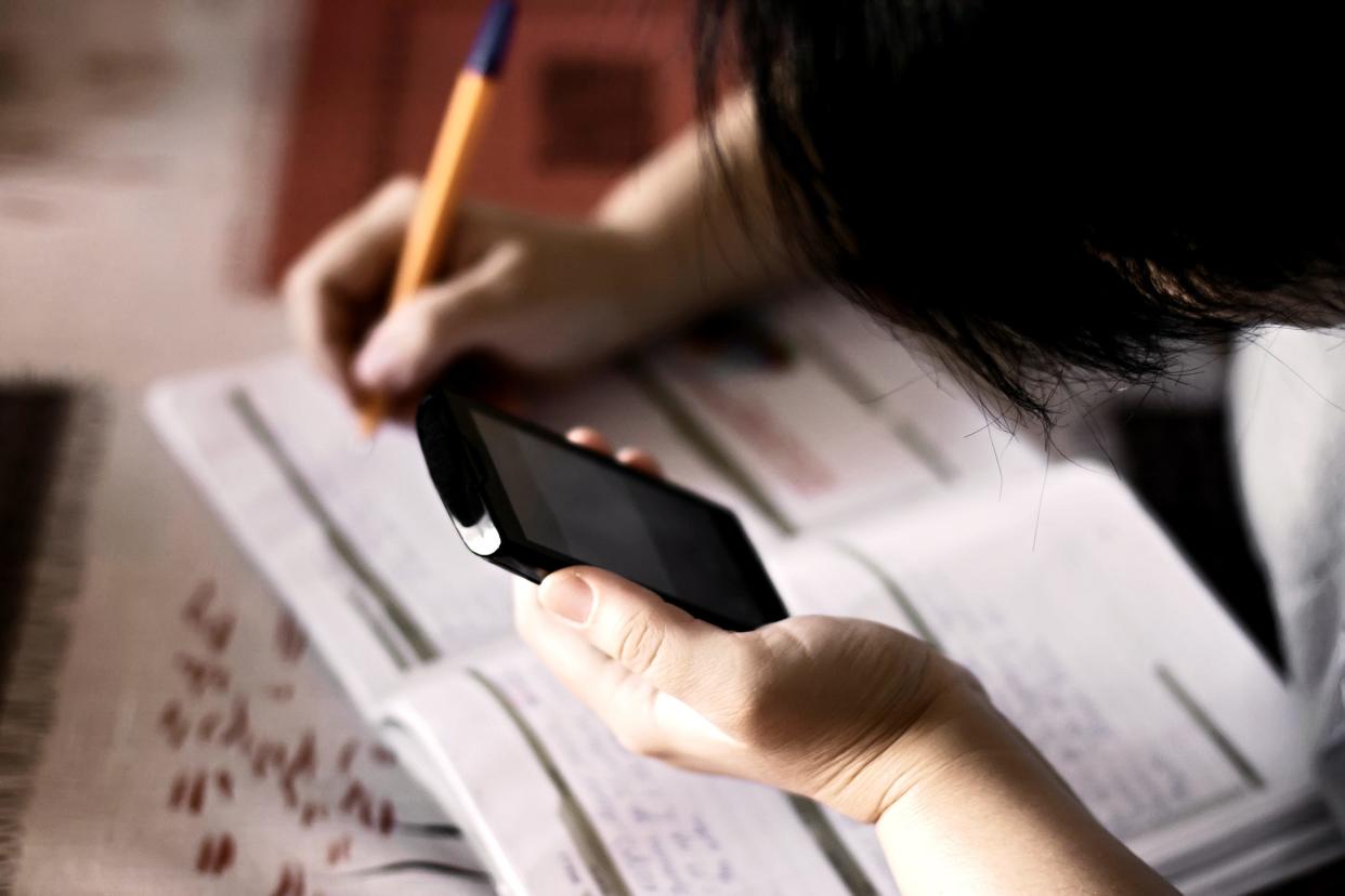 Female student listing homework tasks while using a cellphone.