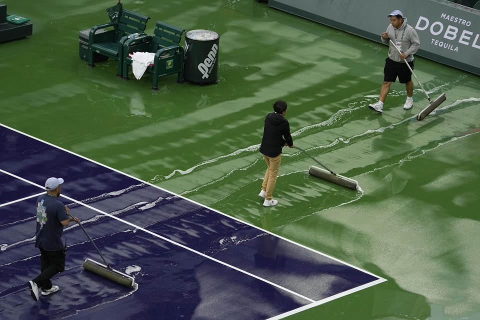 Workers dry off Stadium Court during a rain delay at the BNP Paribas Open tennis tournament Friday, March 10, 2023, in Indian Wells, Calif. (AP Photo/Mark J. Terrill)