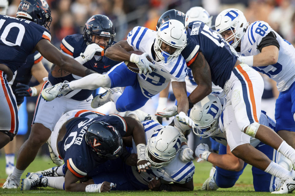 Duke running back Jaylen Coleman (22) dives ahead for a short gain as he is tackled by Virginia defensive end Chico Bennett Jr. (15) during the first half of an NCAA college football game Saturday, Nov. 18, 2023, in Charlottesville, Va. (AP Photo/Mike Caudill)