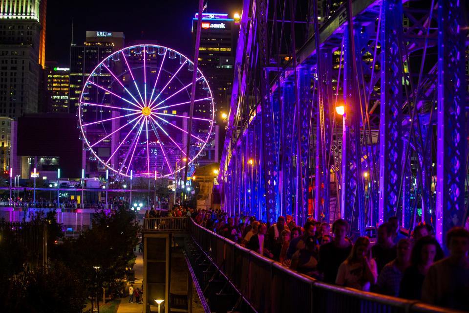 Hundreds of people walk along the Roebling Suspension Bridge as lights are projected on the bridge for Blink in 2019.