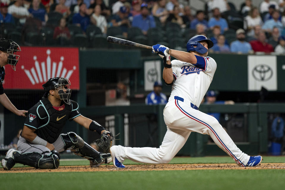 Texas Rangers' Corey Seager follows through on a three-run home run off of Arizona Diamondbacks starting pitcher Brandon Pfaadt, next to Diamondbacks catcher Gabriel Moreno during the fifth inning of a baseball game Tuesday, May 28, 2024, in Arlington, Texas. (AP Photo/Jeffrey McWhorter)