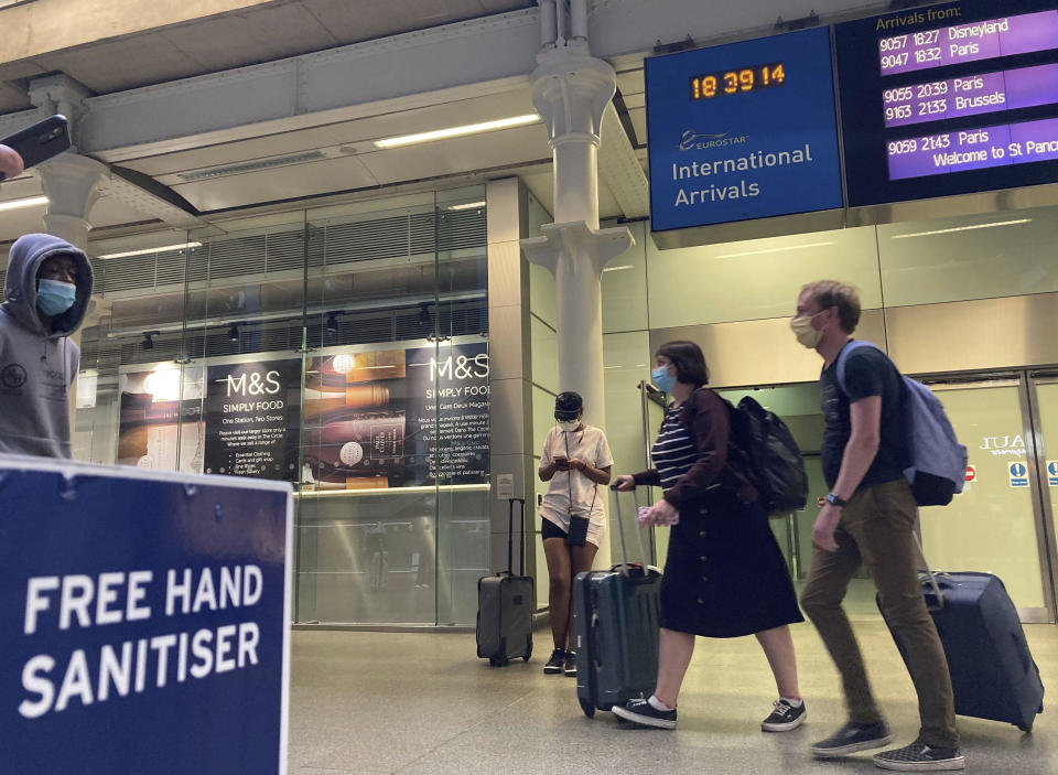 Travelers emerge from the Eurostar St Pancras International railway station, returning from France on Friday to avoid the quarantine restrictions.  Travelers had to return to the UK before a 4 a.m. Saturday deadline to avoid the new restrictions.  / Credit: Kirsty O'Connor/AP