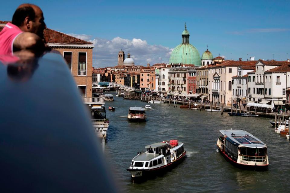 A tourist stands on the Ponte della Costituzione (Constitution Bridge) crossing over the Grand Canal in Venice, on May 16, 2019. (Photo by MARCO BERTORELLO/Getty Images/AFP) 