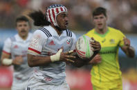 Matai Leuta of the United States, runs with the ball against Australian player in a semi final match of the Emirates Airline Rugby Sevens in Dubai, the United Arab Emirates, Saturday, Dec. 1, 2018. (AP Photo/Kamran Jebreili)