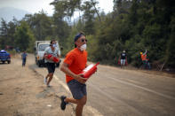 A Turkish volunteer runs as they head to fight wildfires in Turgut village, near tourist resort of Marmaris, Mugla, Turkey, Wednesday, Aug. 4, 2021. As Turkish fire crews pressed ahead Tuesday with their weeklong battle against blazes tearing through forests and villages on the country's southern coast, President Recep Tayyip Erdogan's government faced increased criticism over its apparent poor response and inadequate preparedness for large-scale wildfires.(AP Photo/Emre Tazegul)