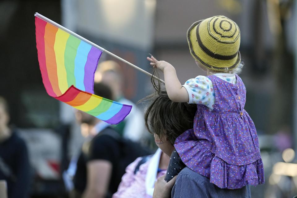 A little girl holds a rainbow flag during a public blessing ceremony with hundreds of believers in front of the Cologne Cathedral in Cologne, Germany, Wednesday, Sept. 20, 2023. Several Catholic priests held a ceremony blessing same-sex and also re-married couples outside Cologne Cathedral in a protest against the city's conservative archbishop, Cardinal Rainer Maria Woelki. (AP Photo/Martin Meissner)