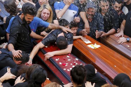 Relatives of the Safwan family, that drowned on a boat carrying them from Turkey to Greece, mourn on their coffins during their funeral in Beirut's southern suburb of Ouzai, Lebanon October 22, 2015. Seven members of a Lebanese family who died trying to reach Greece by boat were buried on Thursday in Beirut and survivors described watching their loved ones perish before their eyes. REUTERS/Mohamed Azakir