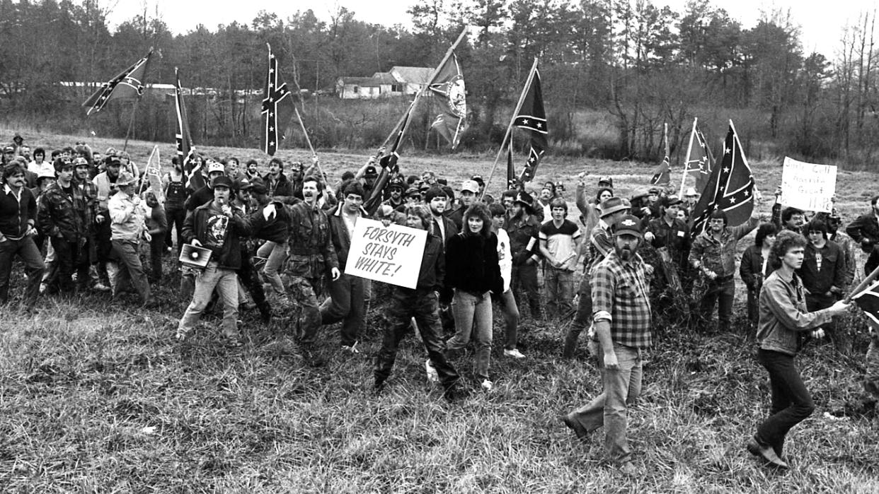 White supremacy activists picketing at a march in Forsyth County, Ga., with Confederate flags and a sign reading: Forsyth stays white!