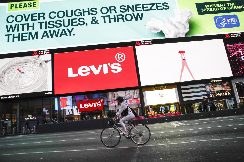 Un ciclista con mascarilla rueda frente a los tradicionales anuncios publicitarios que se pueden ver en Times Square, Nueva York (Estados Unidos). (Foto: John Minchillo / AP).