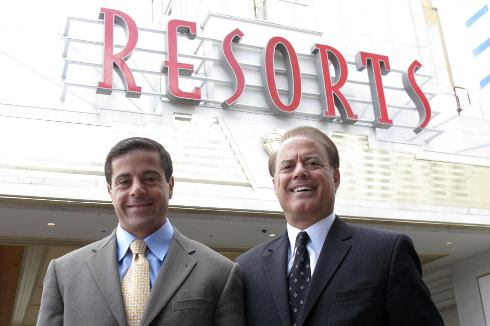 FILE - Aaron Gomes, left, vice president of Resorts Casino in Atlantic City N.J., poses with his father, Dennis, the casino co-owner on July 13, 2011. The elder Gomes died in February 2012, and Resorts hired the Mohegan tribe to run the casino several months later. The Mohegan tribe will end its management of Atlantic City's Resorts casino at the end of this year, both parties said Monday, Feb. 26, 2024. (AP Photo/Wayne Parry, File)