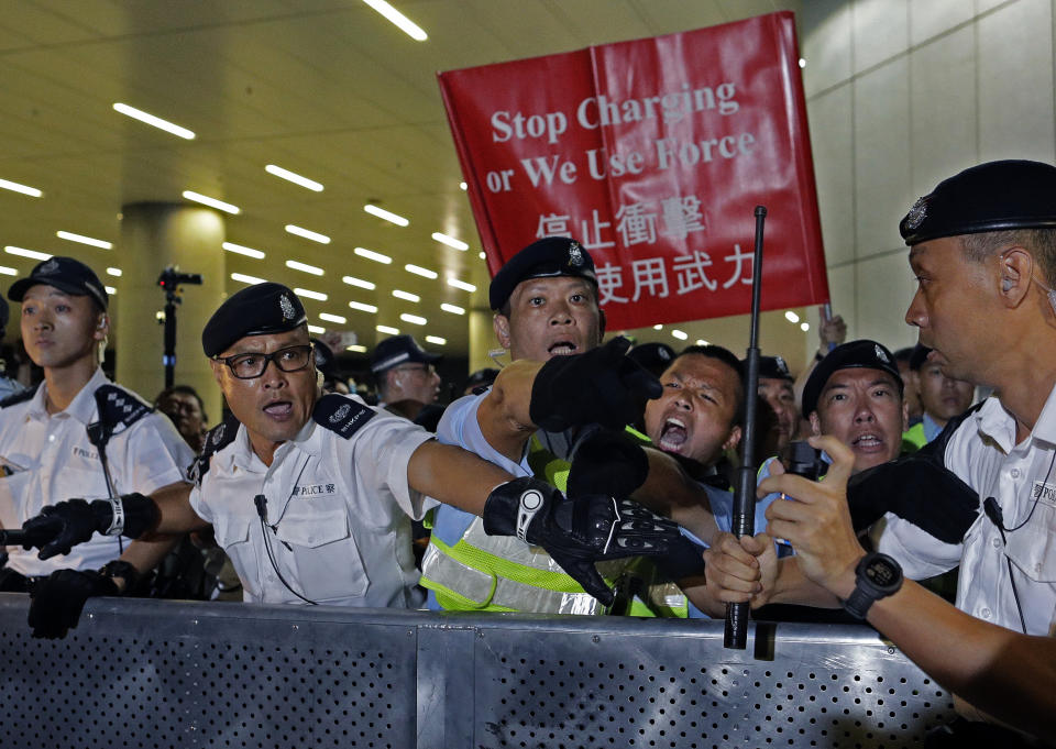 Police officers react as the clash with protesters in a rally against the proposed amendments to the extradition law at the Legislative Council in Hong Kong during the early hours of Monday, June 10, 2019. The extradition law has aroused concerns that this legislation would undermine the city's independent judicial system as it allows Hong Kong to hand over fugitives to the jurisdictions that the city doesn't currently have an extradition agreement with, including mainland China, where a fair trial might not be guaranteed. (AP Photo/Vincent Yu)