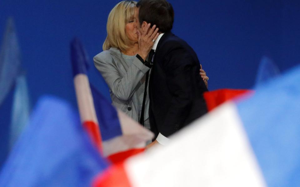 Mr Macron kisses his wife Brigitte Trogneux - Credit: REUTERS/Philippe Wojazer