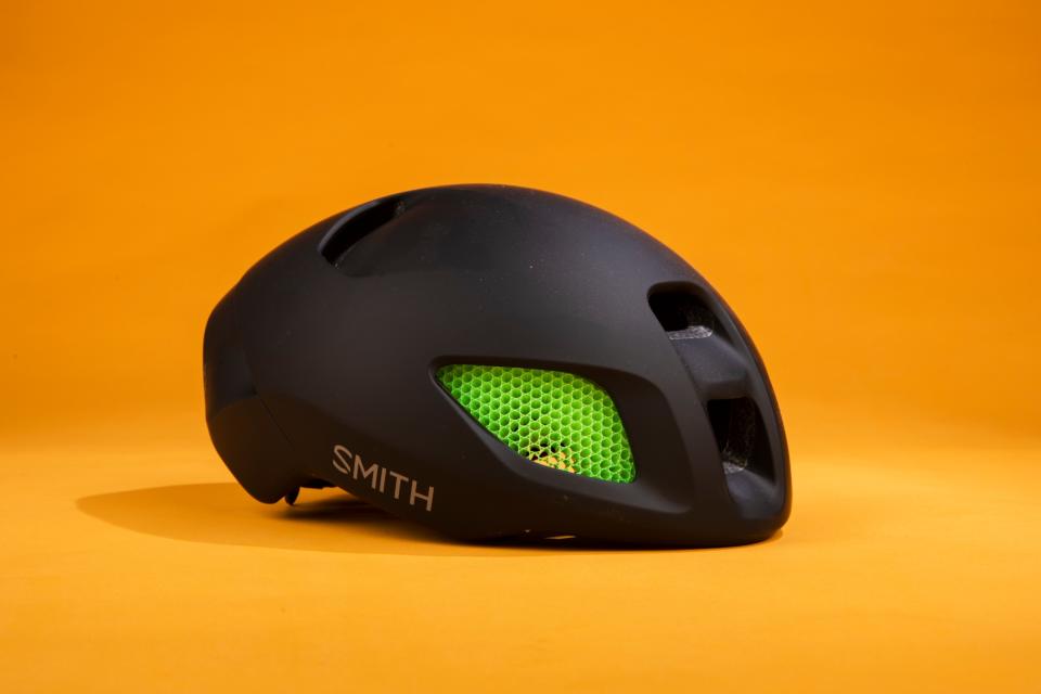 Smith Ignite helmet is pictured front side on in black with green inserts on an orange background