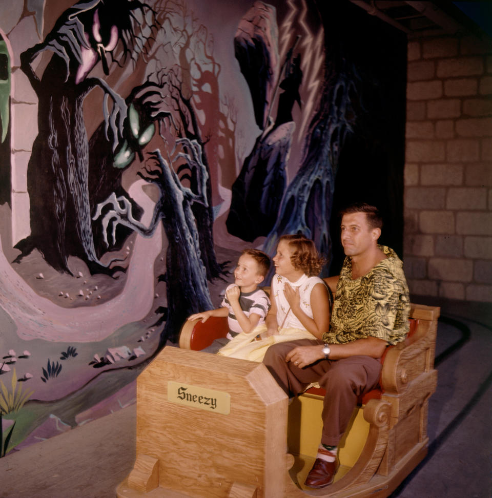 A man and two children move past a scary illustration on the Snow White ride at Disneyland in 1955.