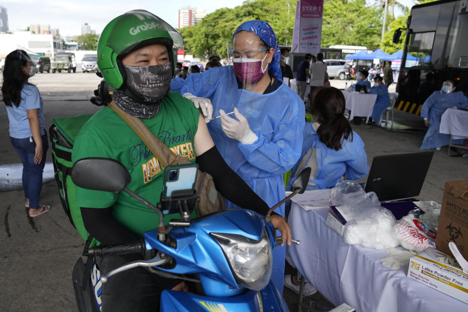 A food delivery driver is inoculated with China's Sinovac COVID-19 vaccine at a drive-thru vaccination center in Manila, Philippines, Tuesday, June 22, 2021. The Philippine president has threatened to order the arrest of Filipinos who refuse COVID-19 vaccination and told them to leave the country for hard-hit countries like India and the United States if they would not cooperate with massive efforts to end the pandemic. (AP Photo/Aaron Favila)