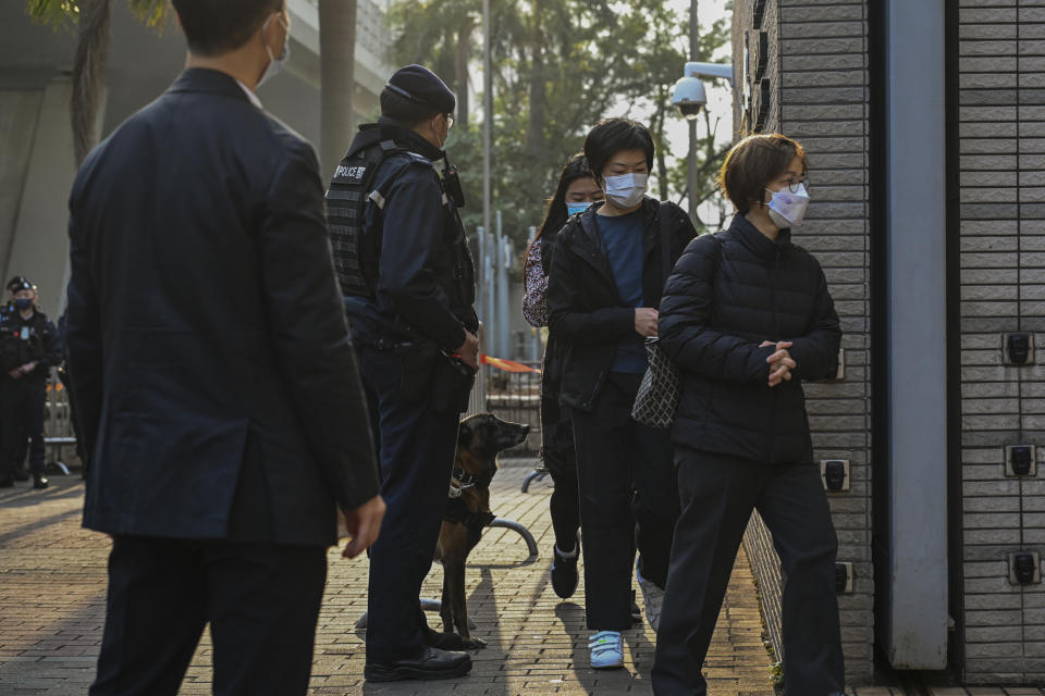 A policeman and a police dog watch over members of the public entering the West Kowloon Magistrates' Courts, where activist publisher Jimmy Lai's trial takes place, in Hong Kong, Tuesday, Jan. 2, 2024. (AP Photo/Billy H.C. Kwok)