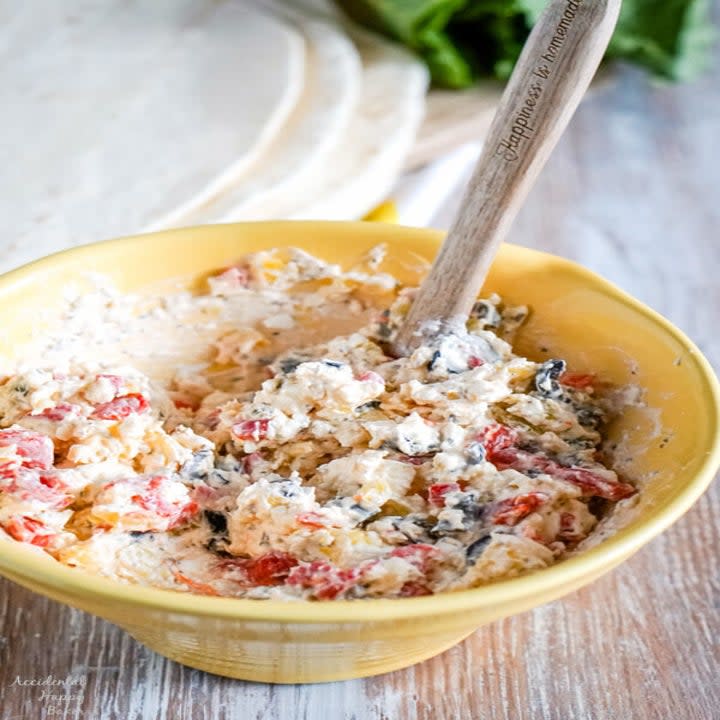 A bowl of pepper and olive cheese spread.