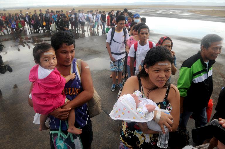 Typhoon survivor Rosel Honrado (R), 24, carries her one-day-old son Ian Daniel as they take a flight on a C-130 military plane out of Tacloban in the Philippines on November 13, 2013