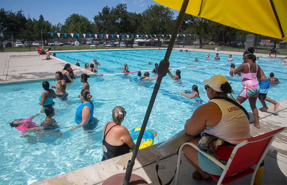 People seek relief from triple-digit temperatures in the waters of the Oak Park Pool in Stockton.