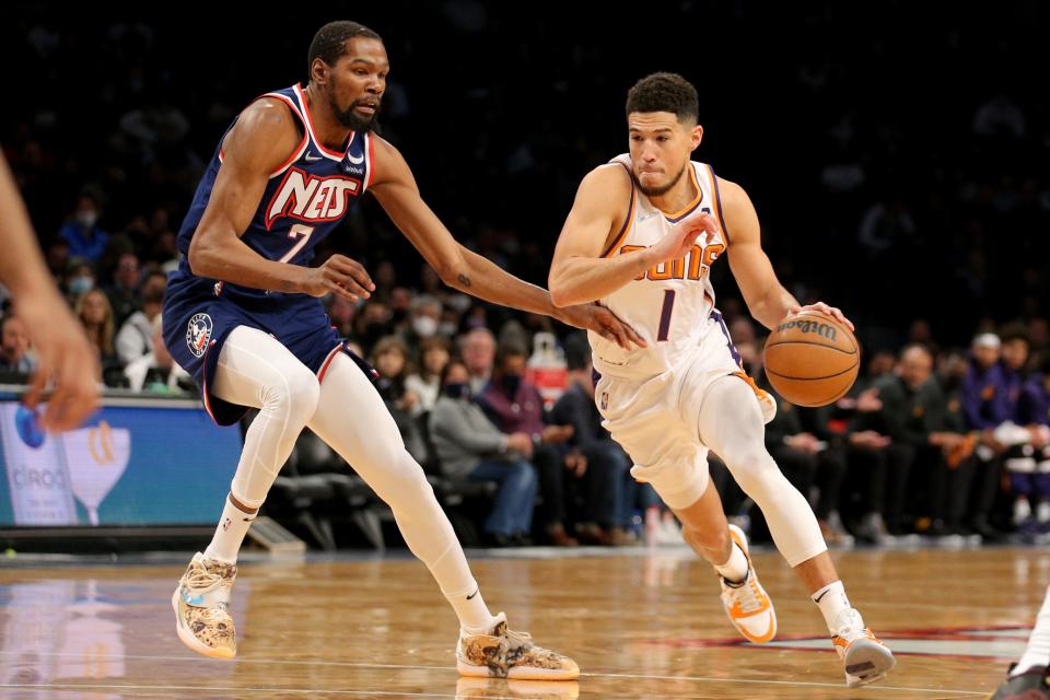 Nov 27, 2021; Brooklyn, New York, USA; Phoenix Suns guard Devin Booker (1) drives with the ball around Brooklyn Nets forward Kevin Durant (7) during the first quarter at Barclays Center.