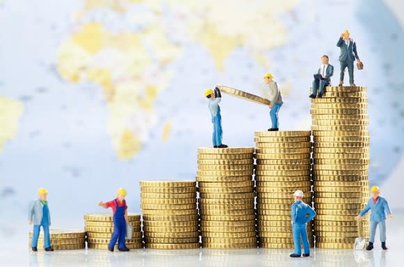 Toy construction workers building stacks of coins that are successively taller.