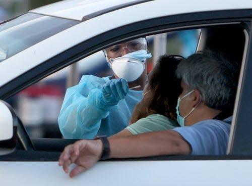 A healthcare worker at a 24-hour drive-thru site set up by Miami-Dade and Nomi Health in Tropical Park administers a COVID-19 test on August 30, 2021 in Miami, Florida.