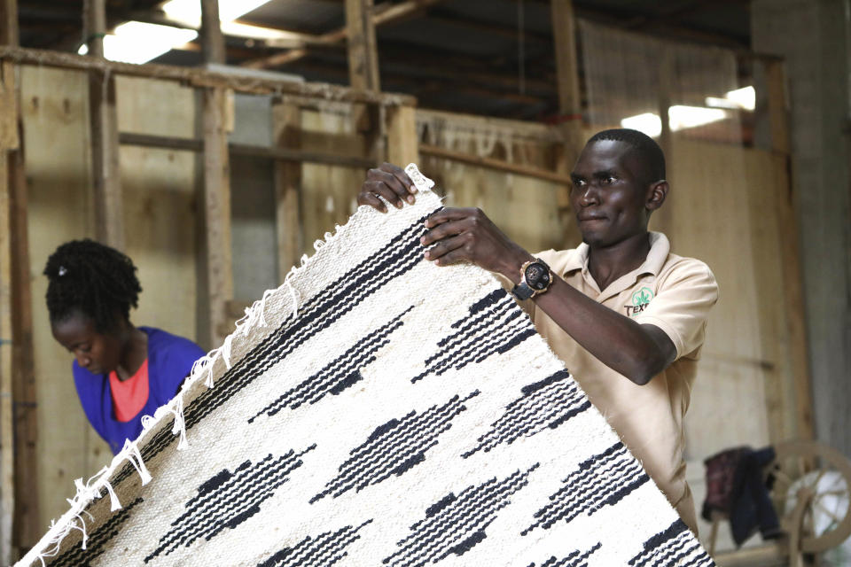 Manager of Texfad, John Baptist Okello checks a handmade carpet woven from banana fiber threads, at Texfad factory in Sonde, Mukono District, Uganda, Wednesday, Sept. 20 2023. The decapitated banana plant is almost useless, an inconvenience to the farmer who must then uproot it and lay its dismembered parts as mulch. A Ugandan company is buying banana stems in a business that turns fiber into attractive handicrafts. The idea is innovative as well as sustainable in this East African country that’s literally a banana republic. (AP Photo/Hajarah Nalwadda)