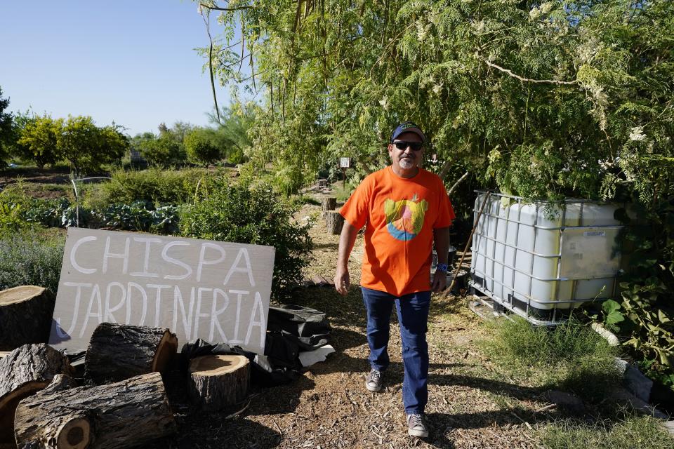 Masavi Perea, organizing director for Chispa Arizona, walks along the pathway of the community garden May 18, 2022, in Phoenix. (AP Photo/Ross D. Franklin)