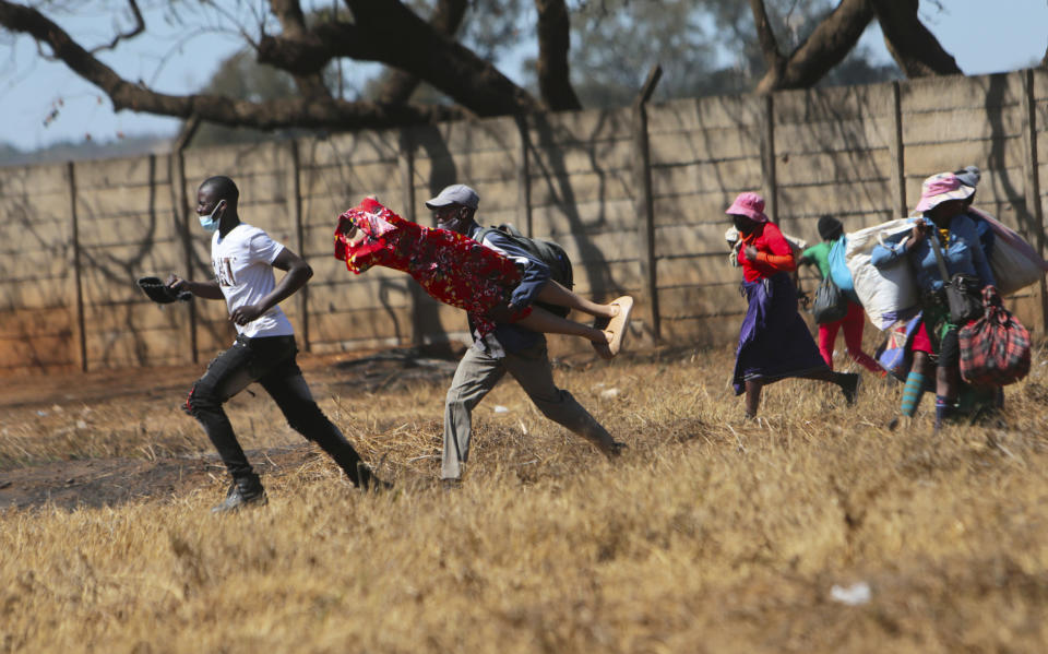 FILE - In this July 29, 2021, file photo, Zimbabwean vendors flee the police after they were chased away from selling their wares in prohibited areas due to COVID-19 restrictions in the capital of Harare. A survey of people aged 18-24 in 15 African countries found that many have lost jobs or have seen their education disrupted by the pandemic. Some say they turn to selling goods on the street to make ends meet. (AP Photo/Tsvangirayi Mukwazhi, File)